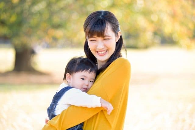 秋の野原で子どもを抱く親